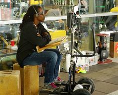 a woman sitting on top of a wooden block next to a radio microphone and headphones