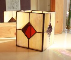 a stained glass block sitting on top of a table next to a mirror with a reflection in it