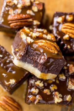 there are many pieces of chocolate with nuts on top and one piece has pecans