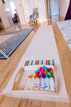 an empty tray with crayons in it on the floor next to a rug