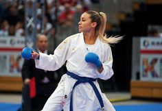 a woman standing on top of a blue mat holding two blue boxing gloves in her hand