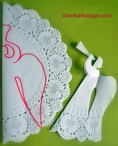 two pieces of paper cut out to look like angels on a doily with scissors