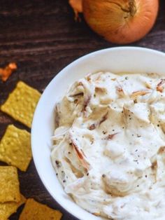 a white bowl filled with dip next to crackers and an orange on the side