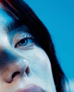 a woman's face with blue and red highlights on her cheek, close up