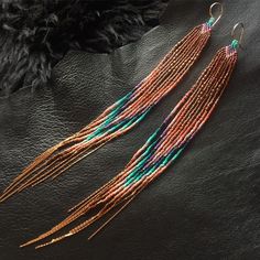 two pairs of multicolored beaded earrings on top of a black leather surface