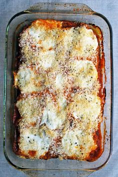 a casserole dish with cheese and sauce in it on a blue table cloth