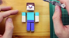 someone is cutting out some paper to make a minecraft creeper figure with scissors