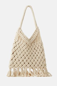 a crocheted bag with tasselled handles