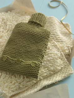 a green knitted mitt sitting on top of a white blanket