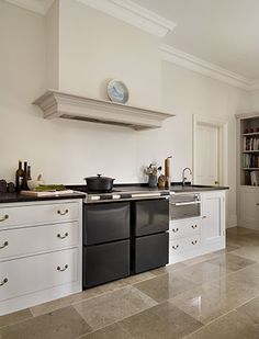 a large kitchen with white cabinets and black stove top oven in the middle of it