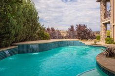 an empty swimming pool in the middle of a home's backyard with blue tiles