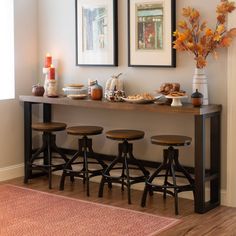 a long table with four stools in front of it and pictures on the wall