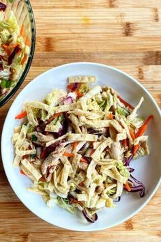 two bowls filled with coleslaw and carrots on top of a wooden table