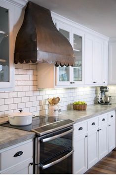 a stove top oven sitting inside of a kitchen next to white cabinets and counter tops