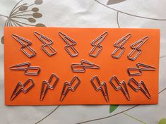 an orange piece of paper with some metal clips on it