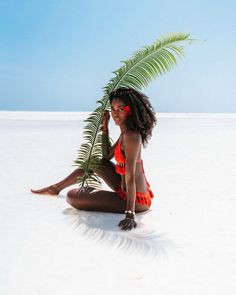 a woman sitting on the ground with a palm tree in her hand