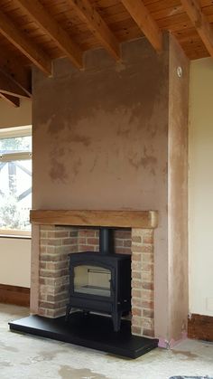 an empty room with a wood burning stove in the center and exposed beams on the ceiling