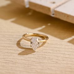 a diamond ring sitting on top of a wooden table next to a piece of wood