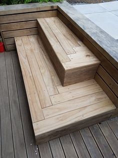 a wooden bench sitting on top of a hard wood floor next to a red trash can