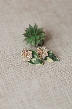 two brooches with flowers and leaves on a table