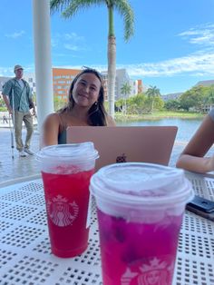 two cups of drinks sitting on top of a table next to each other with people in the background