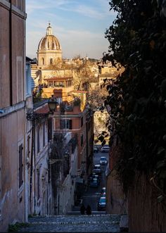 an alley way with cars parked on both sides and a dome in the distance behind it