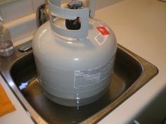 a propane tank sitting on top of a kitchen sink next to a faucet