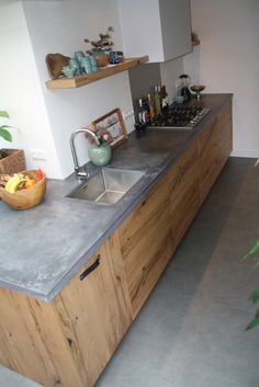 a kitchen with a sink and counter top next to a potted plant in the corner