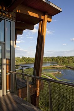 a balcony with a view of a river and trees in the distance, on a sunny day