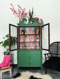 a green cabinet sitting in the middle of a living room filled with furniture and decor