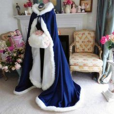 a woman wearing a blue and white cloak in front of a fireplace with flowers on it