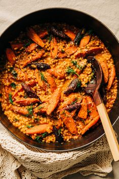 a skillet filled with carrots and lentils on top of a white cloth