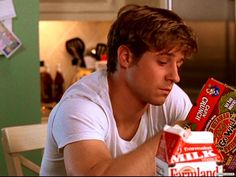 a man sitting at a table with some food in front of him and looking down