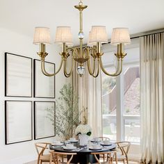 a chandelier hangs over a dining room table in front of a large window