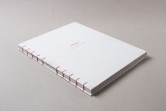 a white book with red lines on the cover is sitting on a gray table top