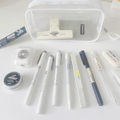 the contents of a travel bag are laid out on top of a white table, including pens and markers