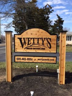 a wooden sign sitting on the side of a road next to a grass covered field