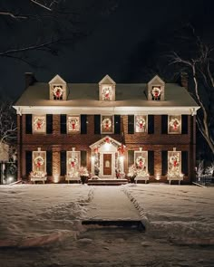 a large brick house with christmas decorations on the windows and lights in front of it