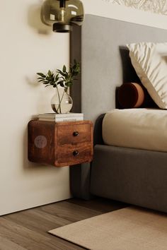 a nightstand with a plant on it next to a bed