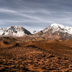 the mountains are covered in snow and brown grass