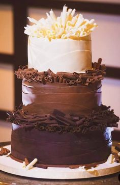 three tiered cake with chocolate icing and flowers on top