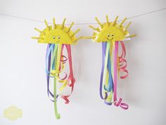 two sun - shaped kites hanging on a string with streamers attached to them