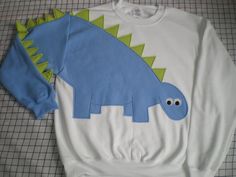 a white sweatshirt with a blue dinosaur on it