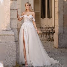 a woman in a white wedding dress standing next to a stone column with her leg up