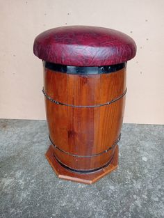 a wooden barrel sitting on top of a cement floor next to a wall with a red leather seat