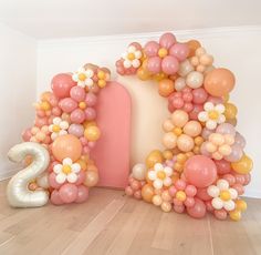 balloons are arranged in the shape of an arch and number two on a wooden floor