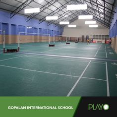 an indoor tennis court with blue walls and green flooring is shown in this image