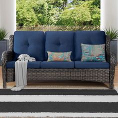 a blue couch sitting on top of a wooden floor next to a white and black rug