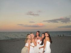 a group of women standing next to each other on a beach