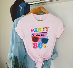 "80s Party Shirt, Party Like 80s Shirt, 80s Fan Shirt, 80s Lover Shirt, 80s Theme Party Shirt, 80s Vintage Shirt,80s Retro Shirt,80s Clothing 🎈HOW TO ORDER 1-) Please, check and review all the photos. 2-) Choose your t-shirt size and color. *Different styles of shirts may have different shades of same color choice due to different manufacturer brands. *For this reason, we recommend you to match shirts from the same styles if you want precisely matching colors (ex. Unisex, V-necks, Toddler, etc.). 3-) Click add to cart. You can go back to add more shirts. 4-)Click \"Proceed to check out\". 5-)When you check out, you can add a note to seller for any request. 🎈PRODUCT DESCRIPTION UNISEX SHIRTS * Unisex t shirt fits like a well-loved favorite, featuring a crew neck, short sleeves and designe 80 Themed Shirt, Vintage Summer Party T-shirt, Retro Pink Party Top, 90s Style Summer Party T-shirt, 90s Inspired Summer Birthday T-shirt, 90s Summer Birthday Tops, 90s Style Summer Birthday Tops, 90s Summer Tops For Birthday, 80s Fashion Women